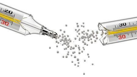 Two fractured glass thermometers lie on a white surface with small silver mercury droplets...