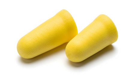 Side showing two yellow foam earplugs lying side by side on a white background. resolution...