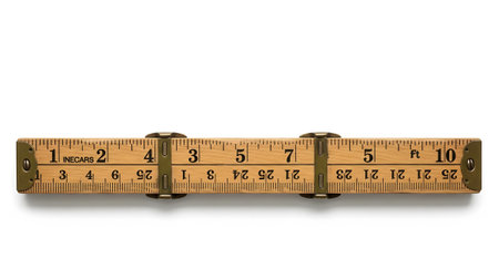 An extended wooden folding ruler with brass hinges and clear inch and foot markings lies on a...