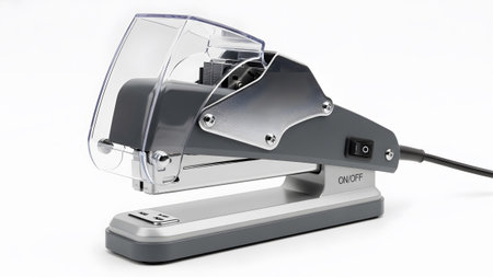 Electric showing gray and silver electric stapler with a clear protective cover and power switch...