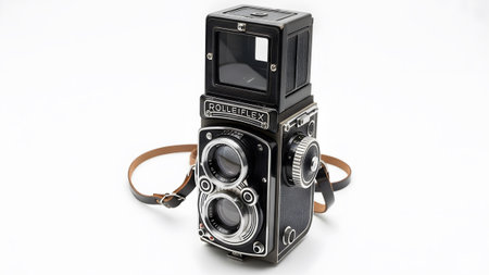 Twin-lens showing vintage twin-lens reflex camera with a leather strap on a white...