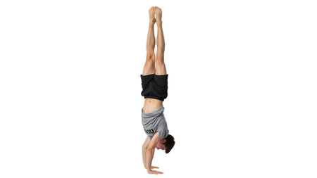 A man performing a handstand with legs extended upwards, wearing athletic clothing, isolated on...