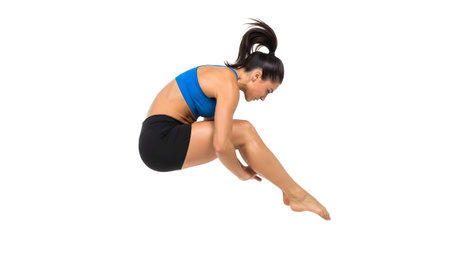 Black showing woman in blue sports bra and black shorts in mid-air gymnastics pose on white....