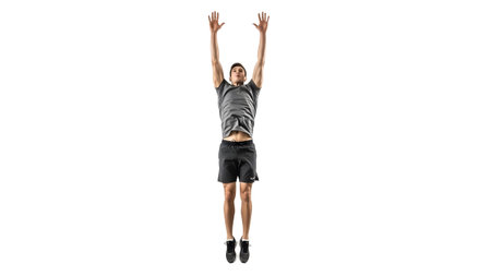 A man in athletic shorts and a grey t-shirt jumps upwards with his arms extended, isolated on a...