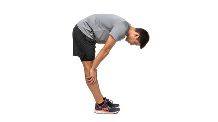 A man in athletic clothing bends forward touching his knees, stretching his legs....