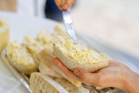 woman hand spreads bread with cheese salad with garlic. the process of preparing a snack for a grill party close upの写真素材
