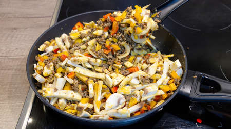 Chef frying minced meat with fresh vegetables in a pan. close upの写真素材