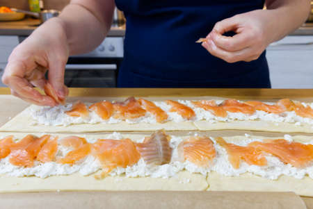 the cook puts spinach and trout on the dough. Savory Christmas pie in the shape of a wreath cooking process. close upの写真素材