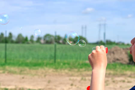 The child blows soap bubbles in nature. close upの写真素材
