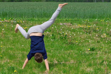 Boy makes an acrobatic wheel. On the grass. close upの写真素材