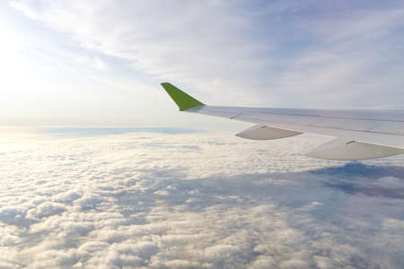 The wing of an airborne aircraft above the clouds. sunny weather and thick clouds. close upの写真素材