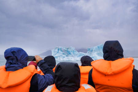 A group of people is taking a boat trip to Jokulsarlon Glacier Lagoon in Iceland. The boat...