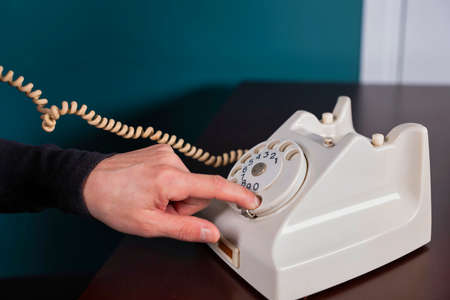 Phone old retro, old fashioned white telephone against green background, woman hand holding telephone cord.の写真素材