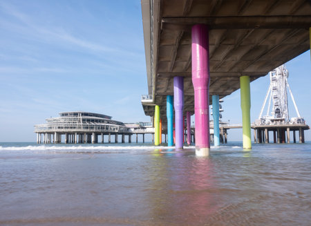 Rainbow colored stone poles under the pier of scheveningen beach the netherlands with sand and waves in the in the sea. Scheveningen, The Netherlandsのeditorial素材