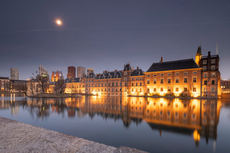 The Hague - February 17 2019: The Hague, The Neherlands. View to the historical Binnenhof with the Hofvijver lake by evening, a blue sky with the moon, in The Hague, The Netherlandsのeditorial素材