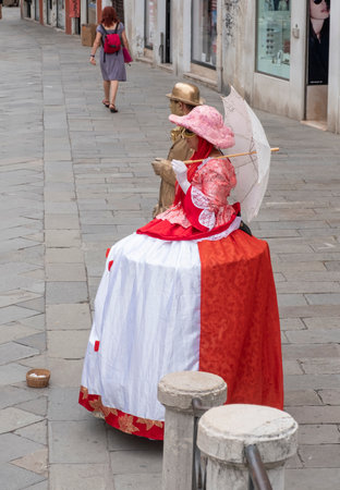 Venice, Italy - June 30, 2017: two people in woman red venetian clothes, man in goldcolored clothes on the street, photographed from above in Venice, Italyのeditorial素材