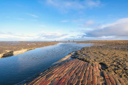 A few people in the distance cleaning up the mess left by a container ship on the beach. the ship has lost a cargo at sea,. Everywhere white balls of styrofoam. Friesland, the Netherlands. Unesco world heritage.の写真素材