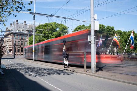 The Hague, May 15, The Hague, The Netherlands. A moving tram at day, a man is waiting at the platform, houses in background, blue sky, long exposure. The Hague, the Netherlandsのeditorial素材