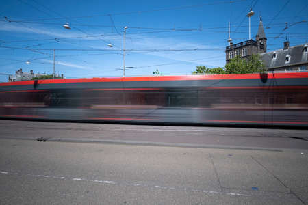 A moving tram at day, houses in background, blue sky, in long exposure. The Hague, the Netherlands.の写真素材