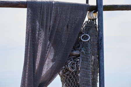 Fishing nets hang from a wooden beam. Against a blue sky. Still life and objects. Fishermen, fishing net.の写真素材