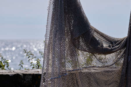 Fishing nets hang to dry in the sun, still lifes and objects. Sea in background. Fishermen, fishing...