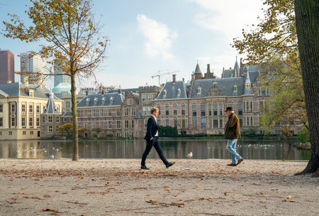 The Hague, November 10, The Hague, The Netherlands. Two men pass each other at a distance of 1.5 meters. Pond, courtyard and seagulls in the background. COVID-19のeditorial素材