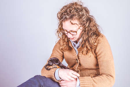 Detail of a beautiful woman with glasses and curly brown hair, Sitting smiling with a Jack Russel...