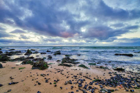 Landscape, seascape sunset on the coast of Huisduinen, the Netherlands. long exposer of waves, dramatic sky, detailed, seaweed, rocks.の写真素材