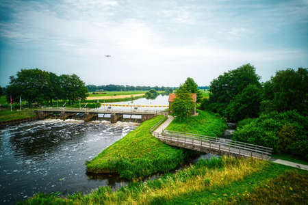 Drone view of the river the Vecht, beautiful blue sky and cycle path. Bridge and weir in the river. Flying drone in the sky. Dalfsen Netherlandsの写真素材