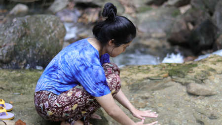 Woman playing Hands on water in a waterfall.の写真素材