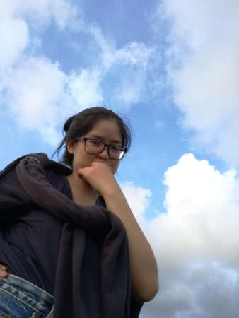 A woman shows a confidence face with blue sky backgroundの写真素材
