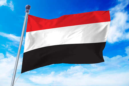 Flag of Yemen developing against a clear blue skyの写真素材