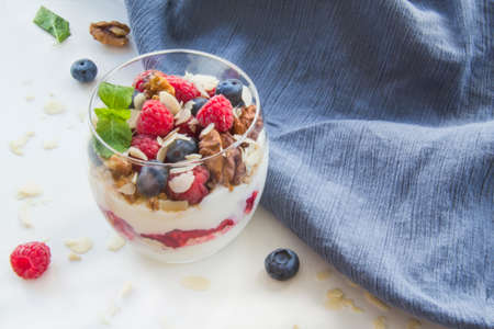 Healthy blueberry, raspberry and walnut parfait in a glass on a white backgroundの写真素材