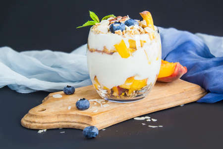 Healthy blueberry, peach and walnut parfait in a glass on a dark backgroundの写真素材