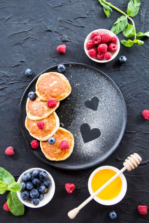 A healthy breakfast of cheese pancakes, berries, and honey. Creative atmospheric decorationの写真素材