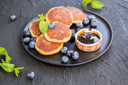 A healthy breakfast of cheese pancakes, berries, and honey. Creative atmospheric decorationの写真素材