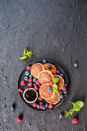 A healthy breakfast of cheese pancakes, berries, and honey. Creative atmospheric decoration