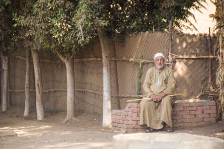CAIRO, EGYPT - DECEMBER 29, 2021: An elderly man sits near a house in a traditional Egyptian village...