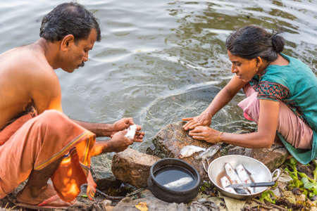 Alappuzha, Kerala, India - December 23, 2015: Keralan man and woman clean fish on the shore of the Pamba River (a part of the Backwaters).のeditorial素材