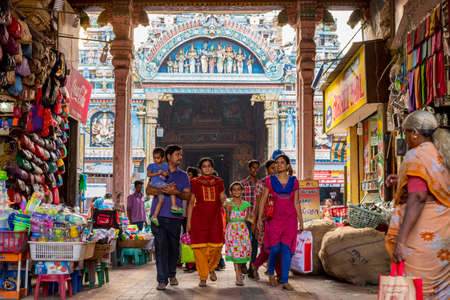 Madurai, Tamil Nadu / India - January 14, 2016: an Indian family walks through an arch occupied by shops, with famous Meenakshi Temple behind. The temple is the main tourist attraction of the city.のeditorial素材