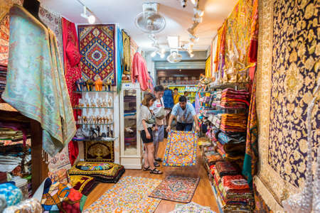 Bangkok, Thailand - July 28, 2019: a seller showcases a rug to customers at a carpet shop at...