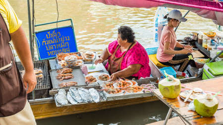 Amphawa, Samut Songkhram / Thailand - June 15, 2019: two vendors cook and sell seafood dishes from a boat at Amphawa Floating Market. One of the most popular floating market in surroundings of Bangkokのeditorial素材