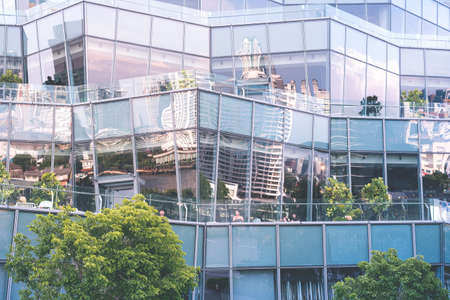 Bangkok, Thailand - June 8, 2019: terraces of IconSiam Shopping mall with resting people and the reflection of the city, the Chao Phraya River and the sky in its glass.のeditorial素材