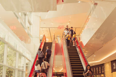Bangkok, Thailand - May 26, 2019: people move at escalators by a large window and the sign of H&M clothing store at the EmQuartier shopping mall.のeditorial素材
