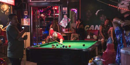 Phnom Penh, Cambodia - January 28, 2019: the interior of Candy Bar with a pool table, a view from the street at night.のeditorial素材