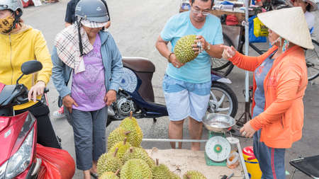Ho Chi Minh City, Vietnam - May 1, 2019: a man buys a durian at a street vendor's place at a street market adjacent to Cho Lon bus station.のeditorial素材