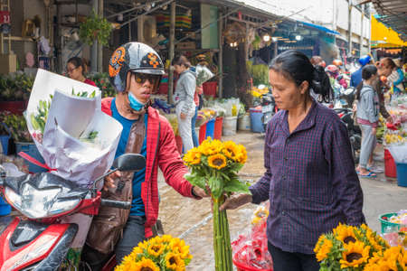 Ho Chi Minh City, Vietnam - April 12, 2019: a woman on motorbike buys a bouquet of flowers from a vendor at Ho Thi Ky Flower Market.のeditorial素材