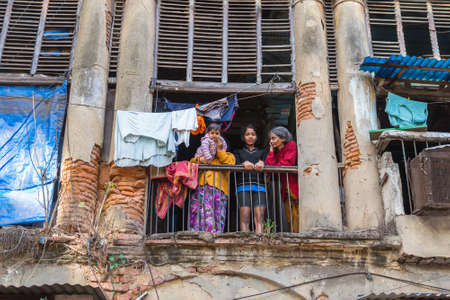 Kolkata, India - January 10, 2015: two women, a girl, and a baby stand on the balcony of an old shabby house with crumbling columns.のeditorial素材