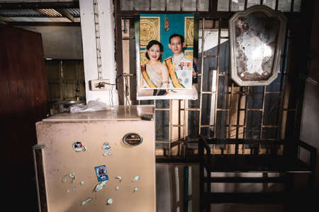 Ubon Ratchathani, Thailand - February 11, 2017: an interior of Thai house with portrait of King Rama IX and Queen Sirikit on wall with old mirror and cutout paper planets, stars & spaceship on fridge.のeditorial素材