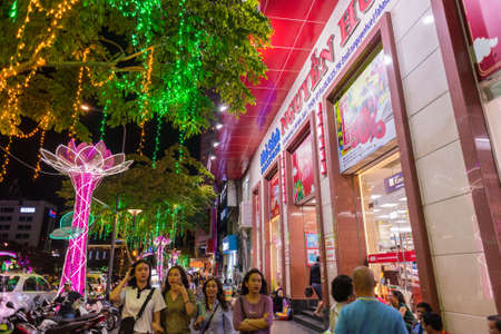 Ho Chi Minh City, Vietnam - February 17, 2019: illuminated Nguyen Hue Street by the Cafe Apartment's bookstore at night with people pass by.のeditorial素材